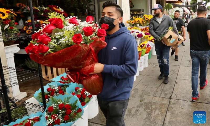 A man carrying a bunch of flowers is seen at a flower market on Mother's Day in downtown Los Angeles, the United States, on May 8, 2022.Photo:Xinhua