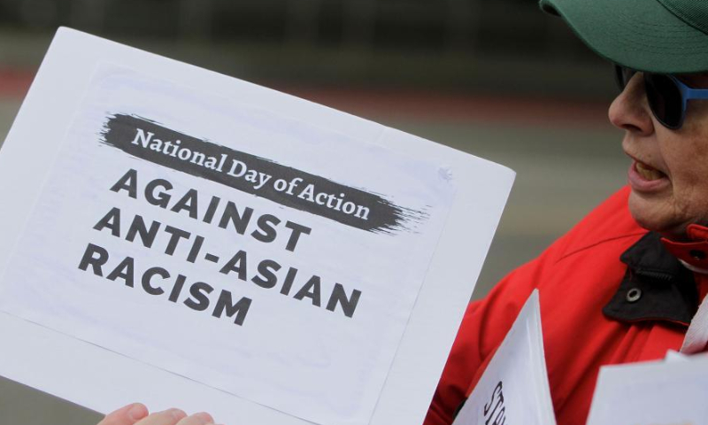 A participant holds a sign during a rally against anti-Asian racism in Vancouver, British Columbia, Canada, on May 10, 2022. (Photo by Liang Sen/Xinhua)