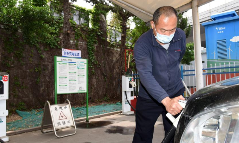 A driver charges his electric car at a shared electric bus charging station in Qingdao, east China's Shandong Province, May 11, 2022. Qingdao City has recently opened some electric bus charging stations to the public. Private vehicles and ride-hailing cars can share the charging facilities together with the public buses. (Xinhua/Li Ziheng)