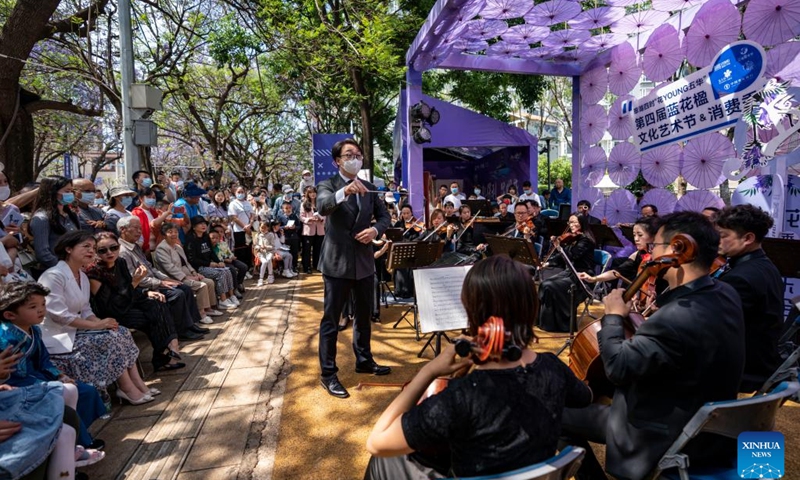 Kunming Nie Er Symphony Orchestra stages a performance for tourists during a Jacaranda-themed concert in Kunming, southwest China's Yunnan Province, May 8, 2022. In recent years, the city has brought more vitality to its tourism markets by combining its jacaranda scenery and cultural creativity.(Photo: Xinhua)