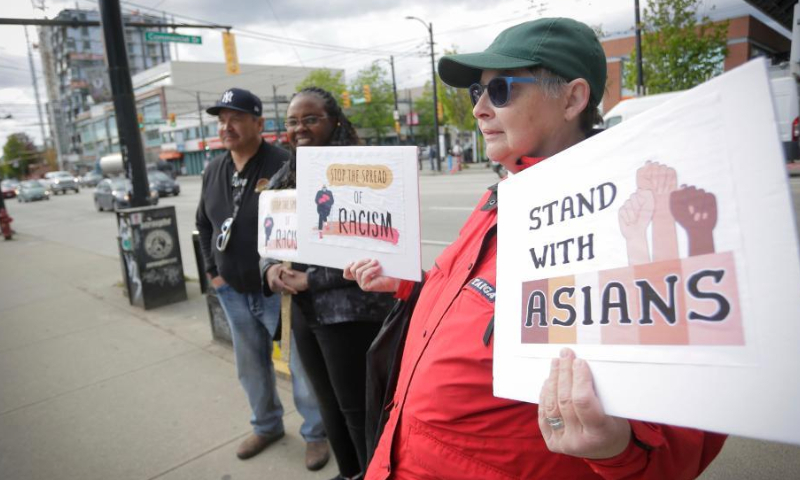 People hold signs during a rally against anti-Asian racism in Vancouver, British Columbia, Canada, on May 10, 2022. (Photo by Liang Sen/Xinhua)