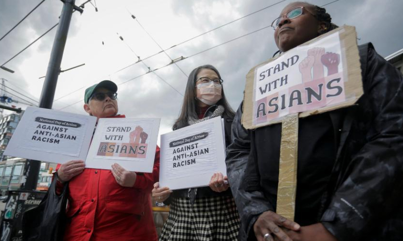 People hold signs during a rally against anti-Asian racism in Vancouver, British Columbia, Canada, on May 10, 2022. (Photo by Liang Sen/Xinhua)