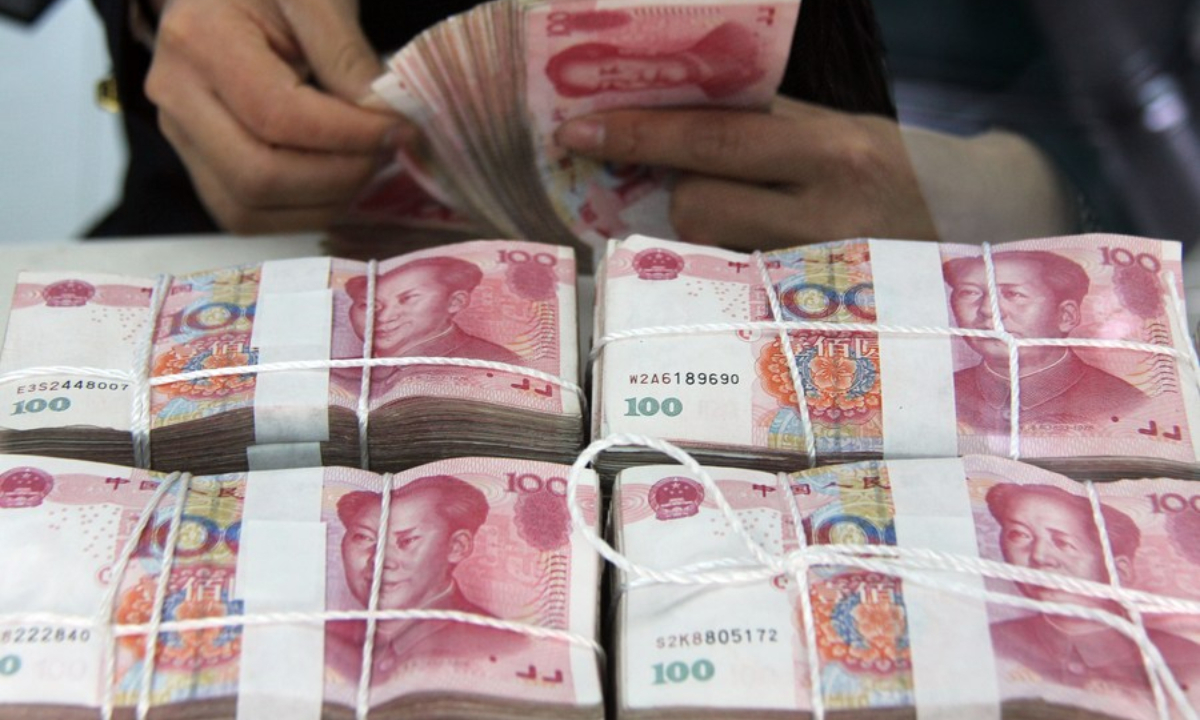File photo shows a worker counts Chinese currency Renminbi banknotes at a bank in Tancheng County of Linyi City, east China's Shandong Province. Photo:Xinhua