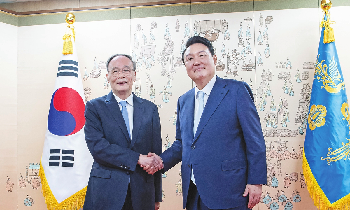Chinese Vice President Wang Qishan (left) shakes hands with South Korean President Yoon Suk-yeol after Yoon's inauguration  at the presidential office in Seoul on May 10, 2022. (See the story on Page 3) Photo:Xinhua
