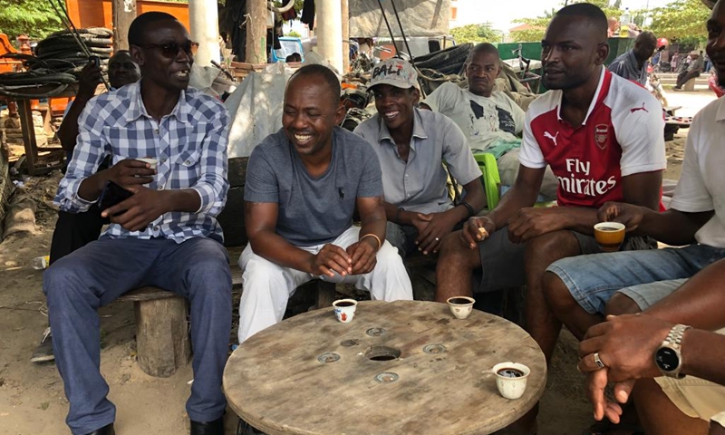People sit and talk at a street coffee stall in Dar es Salaam, Tanzania, in May 9, 2022. Walking in the streets in Tanzania's commercial capital Dar es Salaam's suburbs, one is likely to see people seated under shades of trees drinking coffee at selected locations.(Photo: Xinhua)
