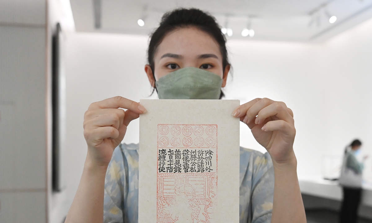 A woman shows a copy of Jiaozi banknotes, the first Chinese paper money, which appeared around the 11th century during the Song Dynasty (960-1279), at the Jiaozi financial museum in Chengdu, Southwest China's Sichuan Province on May 11, 2022. The museum, with an exhibition area of 1,800 square meters, opened on the same day, and it is the first professional museum in China themed around paper money. Photo: cnsphoto
