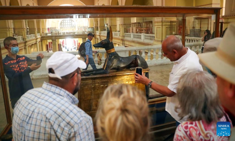 Tourists view the statue of god Anubis discovered at the tomb of king Tutankhamun, at the Egyptian Museum in Cairo, Egypt, on May 14, 2022. As a funerary deity, Anubis is associated with mummification, funerary rituals, and the cemetery in ancient Egyptian myth, usually depicted as a black canine, or a man with canine head. It can be found at large numbers of pharaonic antiquities at the world-known Egyptian Museum. (Xinhua/Sui Xiankai)