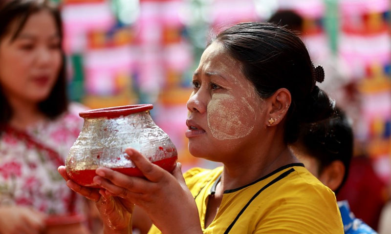 A woman carries a container to water a Bodhi Tree at the Shwedagon Pagoda in Yangon, Myanmar, May 14, 2022.Photo:Xinhua
