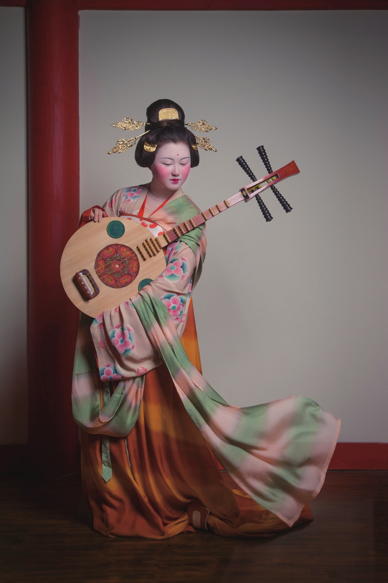 A model poses for a photo in a recreation of a Tang Dynasty (618-907) outfit by the Shanghai-based costumes restoration team. Above: A team member is tiding up a performer's attire before a fashion show. Photos:  Courtesy of Hu Xiao