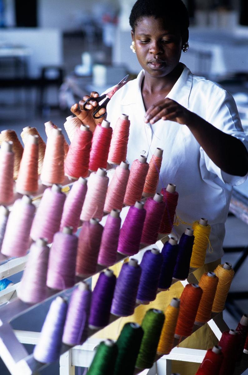 A woman cuts a piece of thread from a row of colorful cotton spools in Zimbabwe. Photo: IC