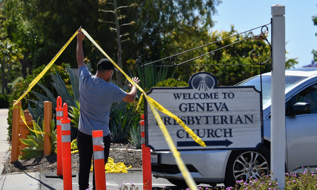 A church staff member raises police tape for a car to exit at the Geneva Presbyterian Church May 16, 2022, after one person was killed and five injured during a shooting the day before at the church in Laguna Woods, California, the US. Photo: AFP