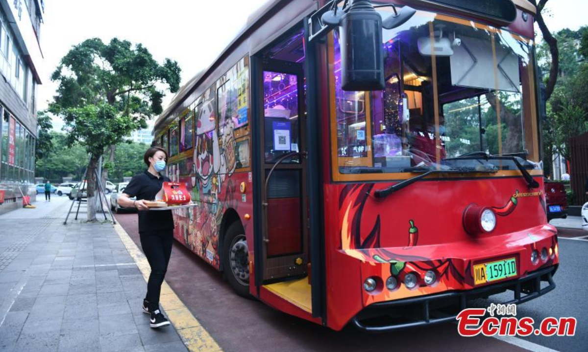 A staff carries pre-cooked hotpot dishes onto the sightseeing bus in Chengdu, southwest China's Sichuan Province, May 19, 2022. Photo:China News Service