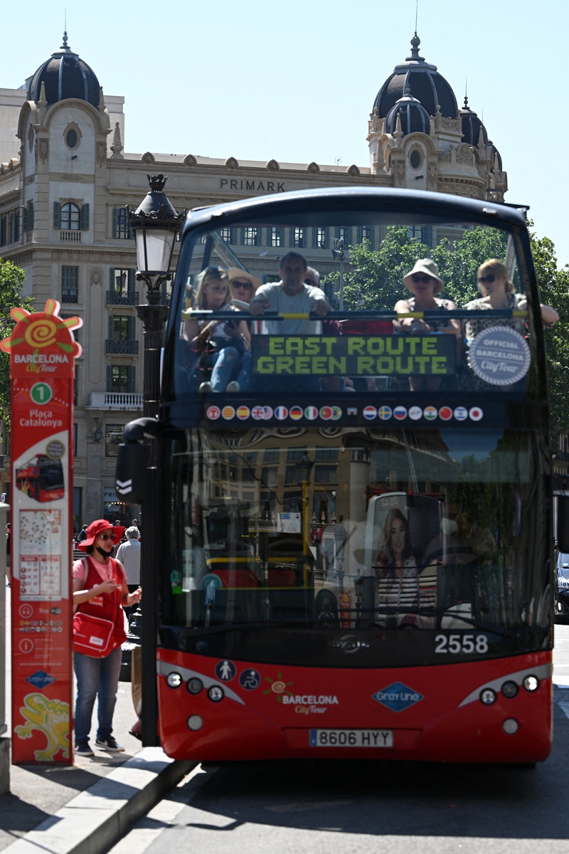 Tourists enjoy a tour bus ride at Plaza Catalunya in Barcelona, on May 11, 2022. Photo: AFP