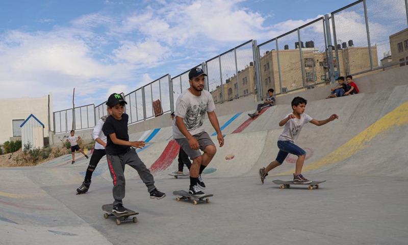 Palestinian young trainer Rajab Al-Rifi (L) gives skateboarding training for Palestinian boys near the northern Gaza Strip town of Beit Lahia, May 20, 2022.Photo:Xinhua