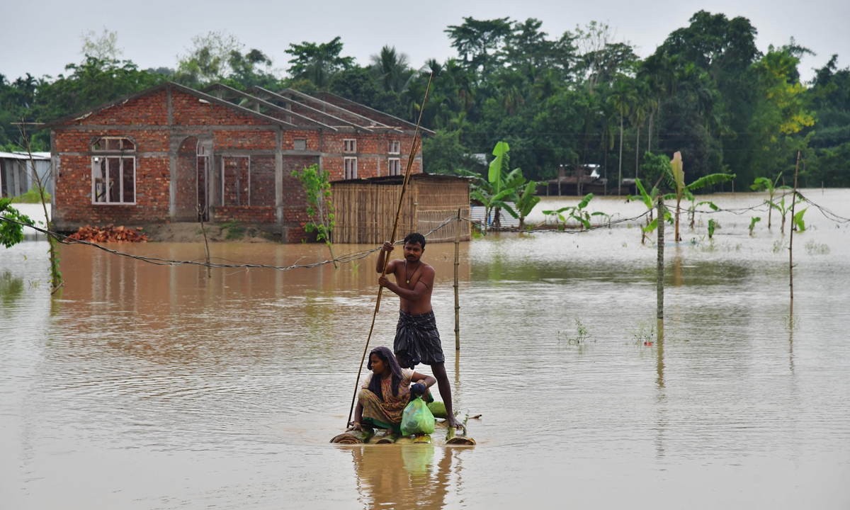 Villagers make their way on a raft past homes in a flooded area after heavy rains in Nagaon district, Assam State, India on May 21, 2022. Heavy rains have caused widespread flooding in parts of Bangladesh and India, leaving millions stranded and at least 57 dead, officials said on May 21, 2022. Photo: AFP