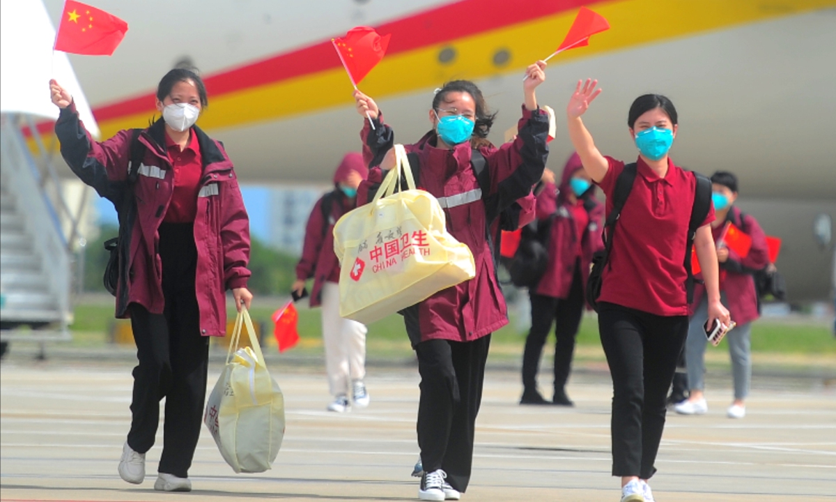 Medical staffers wave Chinese flags upon arriving at an airport in Sanya, South China's Hainan Province on May 23, 2022. Chartered planes carrying 906 members of a medical team who had finished aiding Shanghai's anti-epidemic work arrived at the airport on the day. Photo: VCG