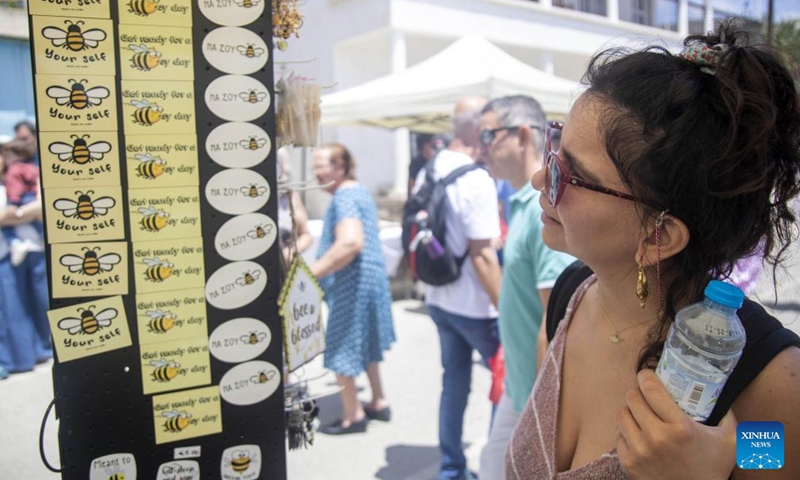A woman looks at bee-themed souvenirs during a bee festival in Ora village in Larnaca, Cyprus, on May 22, 2022.Photo:Xinhua