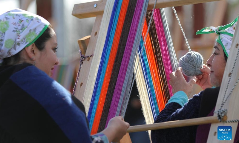 Mapuche women weave in Puerto Saavedra of Araucania, Chile, on May 21, 2022. A total of 426 indigenous Mapuche women from Chile and Argentina completed a loom weaving piece which measures about 900 meters in length, seeking to break a world record.Photo:Xinhua