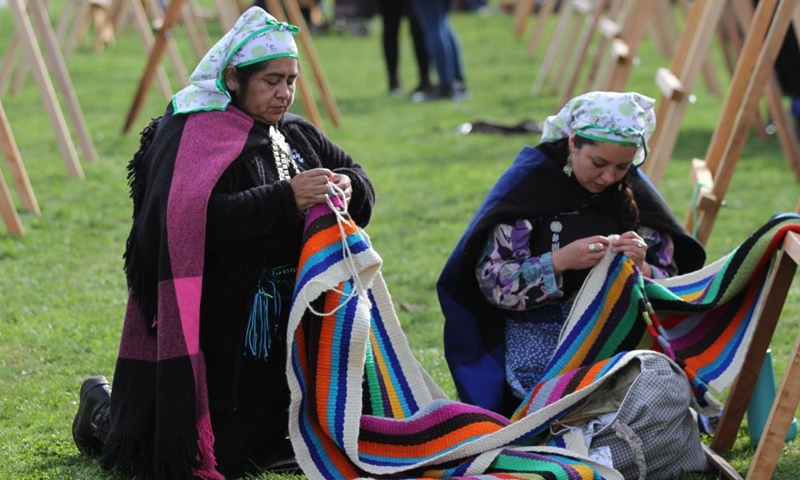Mapuche women weave in Puerto Saavedra of Araucania, Chile, on May 21, 2022. A total of 426 indigenous Mapuche women from Chile and Argentina completed a loom weaving piece which measures about 900 meters in length, seeking to break a world record.Photo:Xinhua