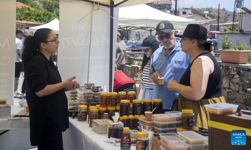 A bee products seller talks with visitors during a bee festival in Ora village in Larnaca, Cyprus, on May 22, 2022.Photo:Xinhua
