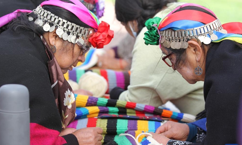 Mapuche women weave in Puerto Saavedra of Araucania, Chile, on May 21, 2022. A total of 426 indigenous Mapuche women from Chile and Argentina completed a loom weaving piece which measures about 900 meters in length, seeking to break a world record.Photo:Xinhua
