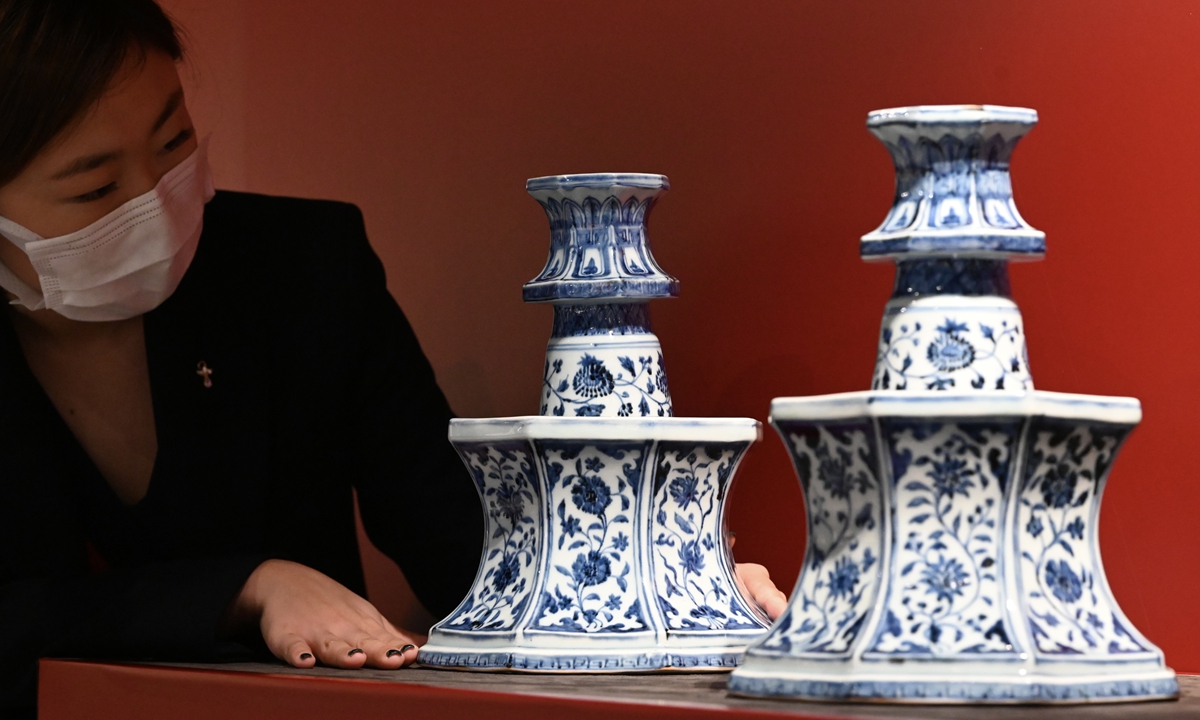 A staff member of Bonhams Auction House in Hong Kong shows blue and white porcelain made during the Ming Dynasty (1368-1644) - a pair of candlesticks, estimated at HK$15 million ($1.91 million) to HK$25 million, during a media preview on May 24, 2022. Photo: VCG