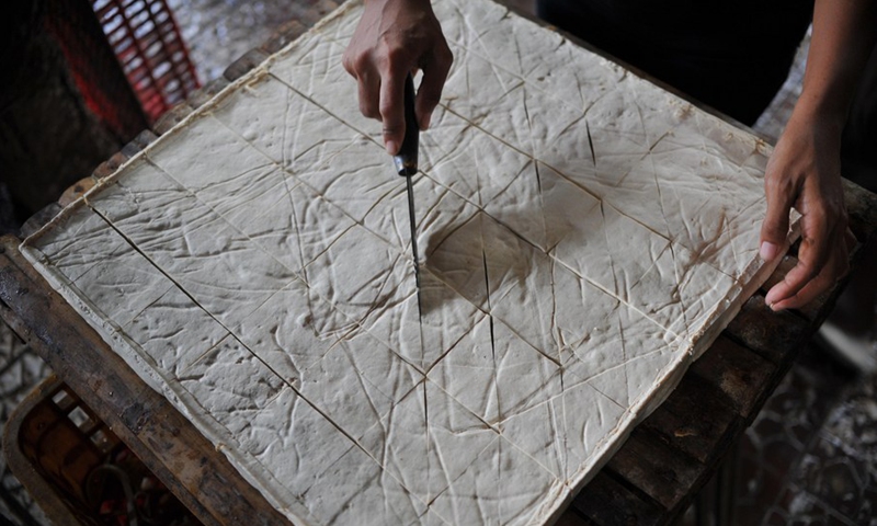 An Indonesian worker cuts tofu at a small-scale tofu factory in South Tangerang, Banten Province, Indonesia, July 10, 2019.(Photo: Xinhua)