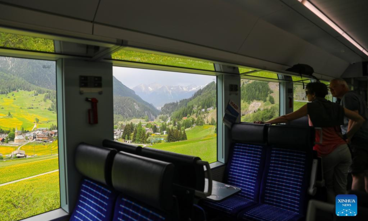 Passengers look at the view on a train that runs on the Rhaetian Railway in the Albula/Bernina landscapes in Switzerland, May 22, 2022. The Rhaetian Railway in the Albula/Bernina landscapes was included in the UNESCO World Heritage List in 2008. Photo:Xinhua