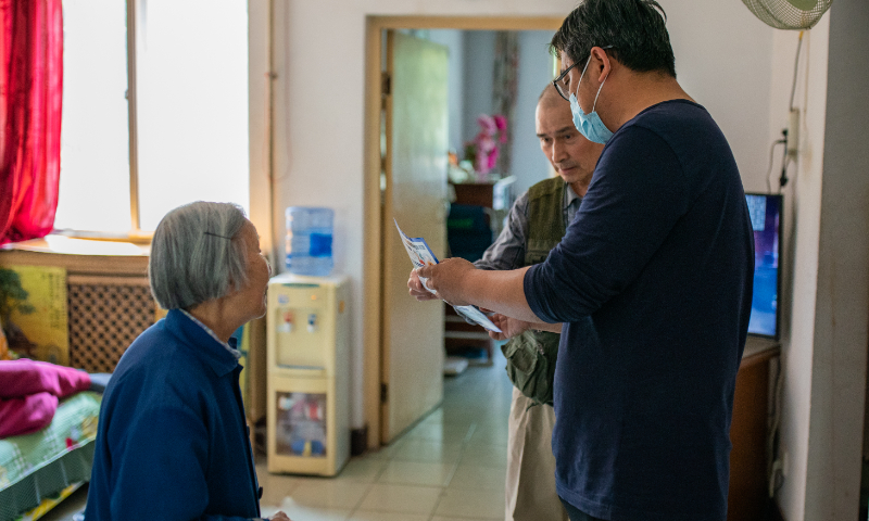 An anti-epidemic worker promotes COVID-19 vaccination information to elderly residents in Beijing on May 18, 2022. Photo: VCG