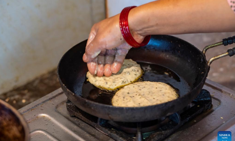 A Nepalese cooks special pancake with green and black lentils during Sithi Nakha Festival in Lalitpur, Nepal, June 5, 2022. The Newar community celebrates the Sithi Nakha festival to mark the beginning of monsoon season by cleaning water sources such as ponds, wells and stone spouts. People also prepare traditional pancakes such as Bara and Chatamari as a tribute to their ancestral god. Photo: Xinhua