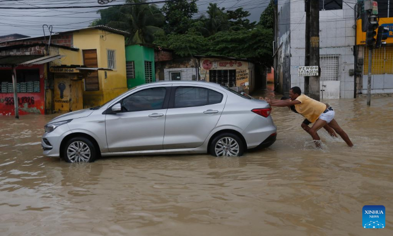 People push a car on a flooded street after heavy rains in Recife, Brazil, June 3, 2022. The death toll from heavy rains in Recife, capital of the Brazilian state of Pernambuco, and its metropolitan area has risen to 128, local authorities said Friday. (Photo by Lucio Tavora/Xinhua)