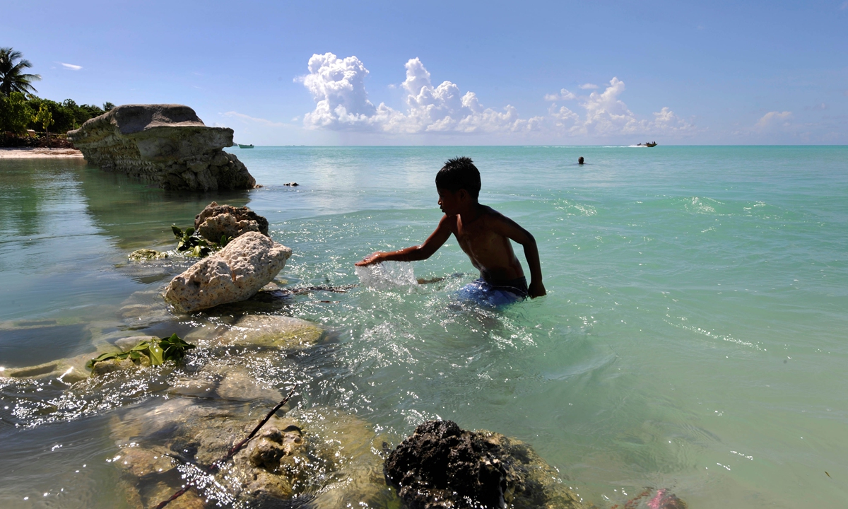 A boy plays at the sea wall in the village of Eita on the island of Tarawa, Kiribati. The sea wall has been destroyed by rising tides. Photo: VCG