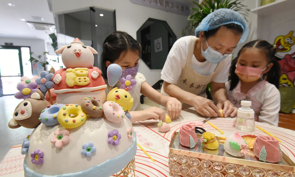 A staffer at a food shop in Handan, North China's Hebei Province, teaches children to make decorated steamed buns, an intangible cultural heritage of Hebei, on May 31, 2022.  The lesson took place ahead of the International Children's Day. Photo: IC 