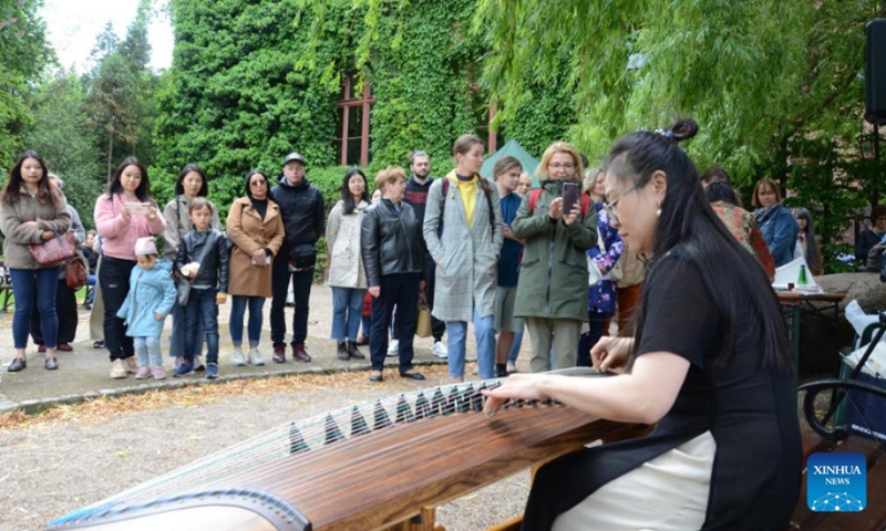 A woman performs Guzheng, a Chinese zither, during China Day, an event jointly held by the Confucius Institute and the Botanical Garden of the University of Wroclaw, in Wroclaw, Poland, May 28, 2022. (Xinhua/Chen Chen)