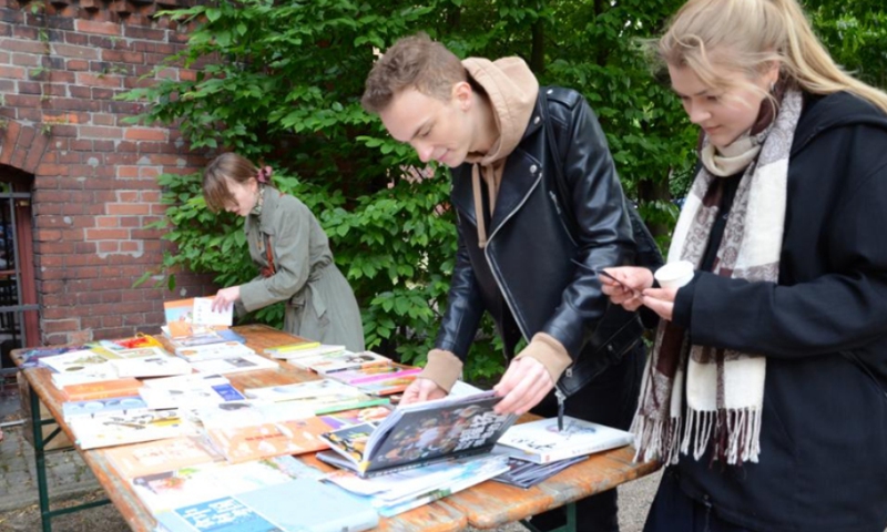 People read books about Chinese food culture during China Day, an event jointly held by the Confucius Institute and the Botanical Garden of the University of Wroclaw, in Wroclaw, Poland, May 28, 2022. (Xinhua/Chen Chen)