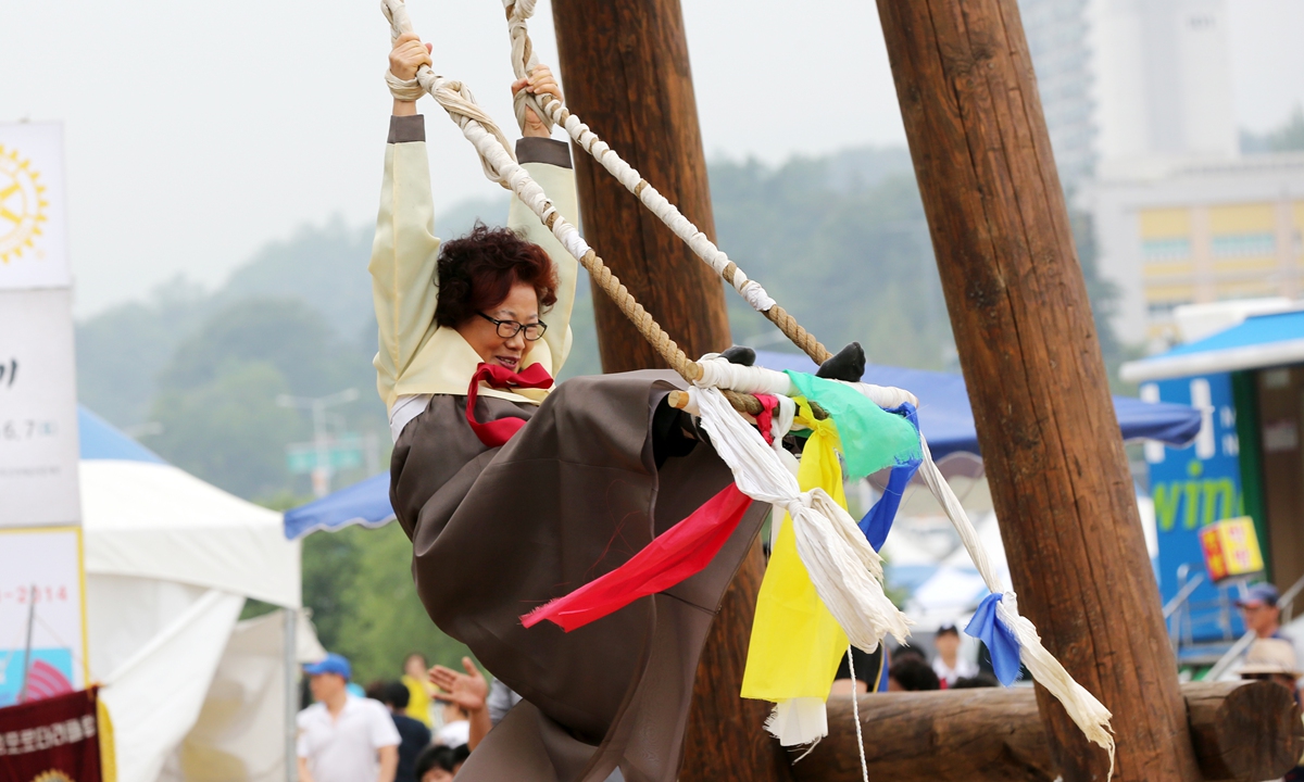 A woman helps a girl rinse her hair with iris water at a Dano event in the Korean Folk Village in Yongin city, South Korea. Photos: IC Top: Teams take part in the Chinese Dragon Boat Festival on June 18, 2016.
Left: A woman plays on a swing during the Korean Dano festival. 