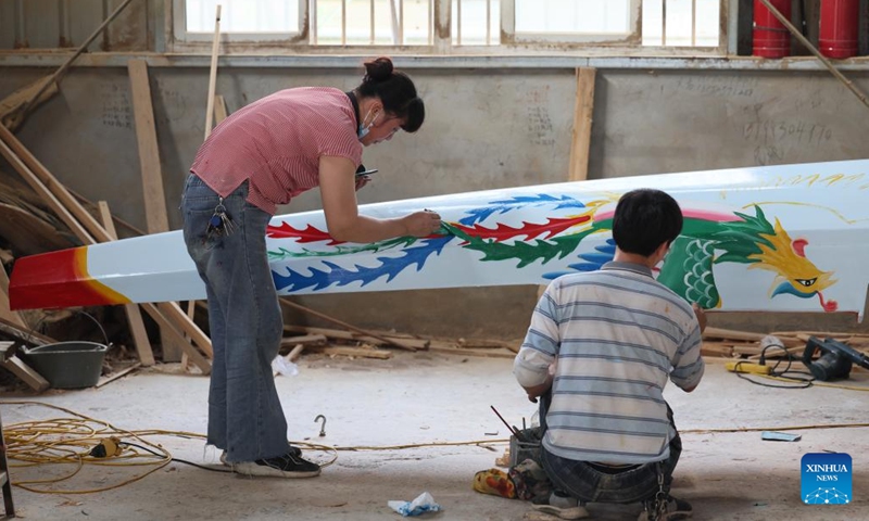 Painter Pan Shujian and his wife paint traditional patterns on a newly made dragon boat at Fanghegang dragon boat factory in Fangzhuang Village of Nantong Township in Minhou County of Fuzhou, southeast China's Fujian Province, May 30, 2022. Fangzhuang, known as Dragon Boat Village, has a traditional dragon boat manufacturing history for more than 700 years. Every year, more than 200 hand-made wooden boats, carefully built by craftsmen, are sold nationwide and even overseas from the village.(Photo: Xinhua)