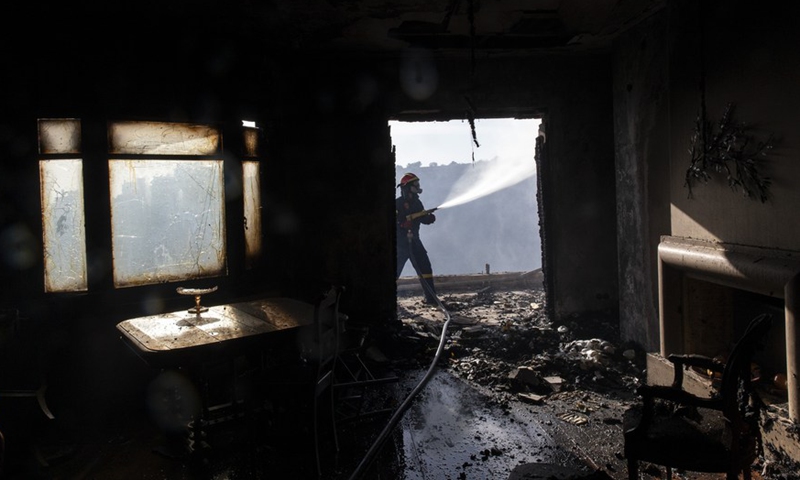 A firefighter battles a fire outside a house in Voula, a southern suburb of Athens, Greece, on June 4, 2022.Photo:Xinhua
