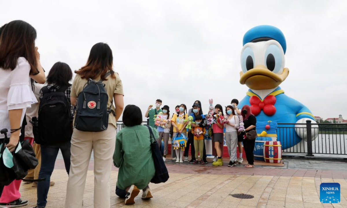 Tourists pose with an inflatable doll of Donald Duck at Wishing Star Park of Disney Resort in Shanghai, east China on June 10, 2022. Shanghai Disney Resort partially resumed operations on Friday as the COVID-19 epidemic wanes in the city. Wishing Star Park, the World of Disney Store and Blue Sky Boulevard resumed operations first and Shanghai Disneyland would remain temporarily closed until further notice. Photo:Xinhua