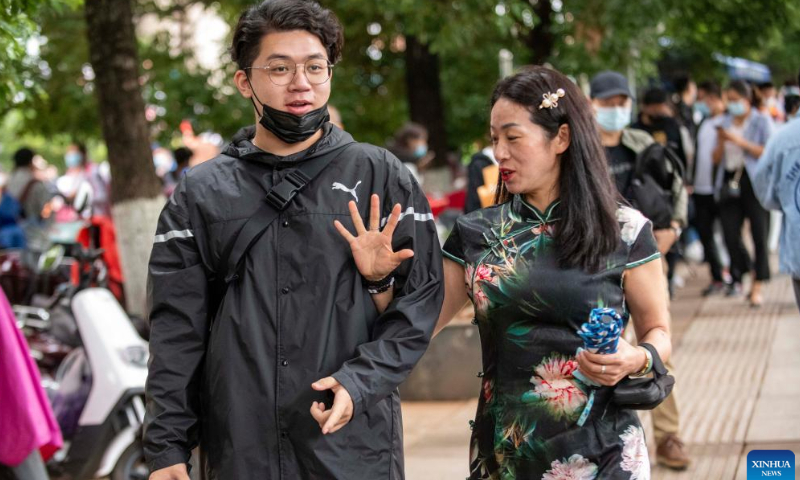 A mother wearing traditional qipao dress leaves with her son after the national college entrance exam in Kunming, southwest China's Yunnan Province, June 8, 2022.  Photo: Xinhua