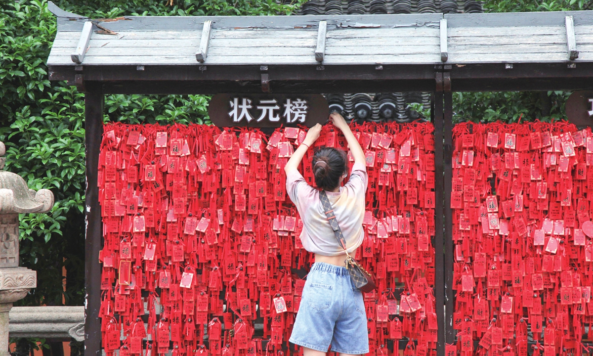 A parent stands on tiptoe to hang a wishing board in front of the wishing wall at the Confucius Temple in Nanjing, East China's Jiangsu province, on June 5, 2022. Photo: IC