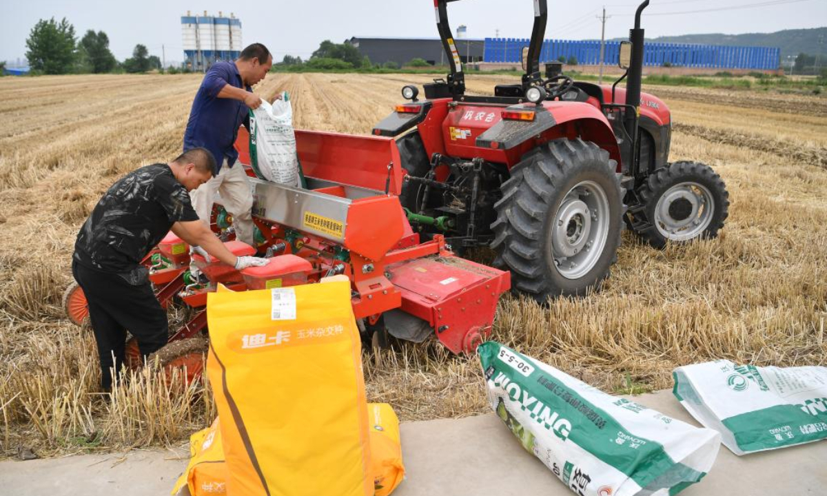 Farmers pour corn seeds and fertilizer into a planter in Gongjiaquan Village of Dongguan Street in Chencang District, Baoji City, northwest China's Shaanxi Province on June 9, 2022. Baoji city has carried out the sowing of autumn grain after the harvest of summer grain. Photo:Xinhua