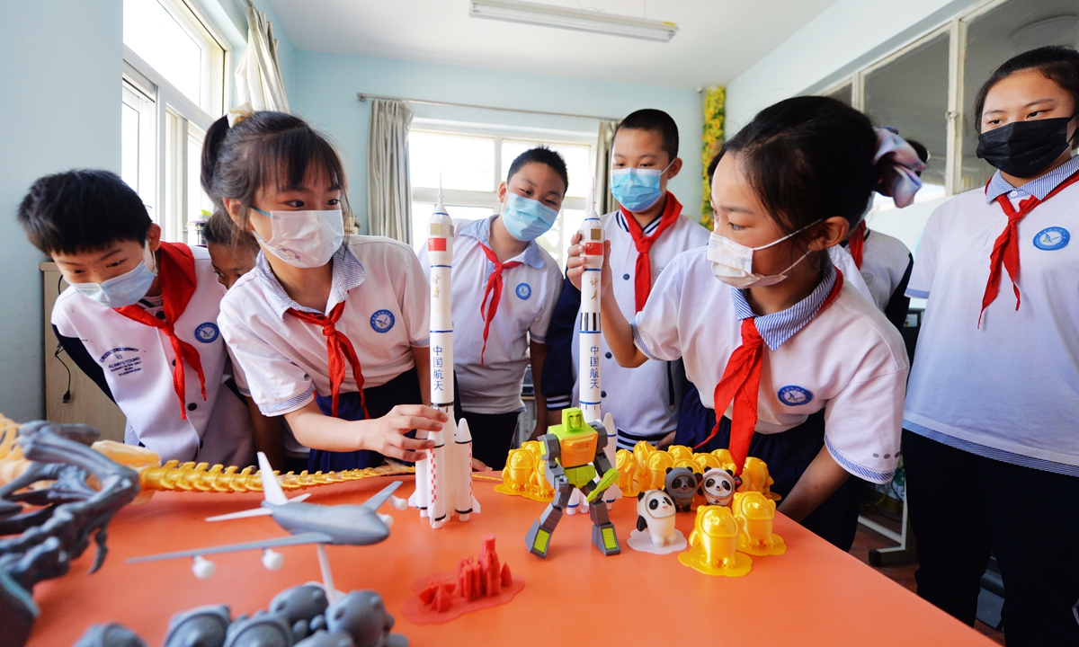 Primary school students look at a printed 3D model of Shenzhou-13 during a campus science festival in Qingdao, East China's Shandong Province, on May 24, 2022. Photo: IC