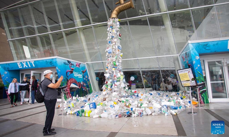A man takes photos of the art installation Turn Off The Plastic Tap outside the Ripley's Aquarium of Canada in Toronto, Canada, on June 7, 2022. The art installation Turn Off The Plastic Tap is on display here to raise awareness of the plastic pollution problem.(Photo: Xinhua)
