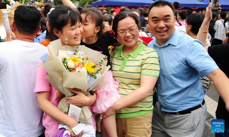 An examinee holding a bunch of flowers poses for a photo with her parents out of an exam site of national college entrance exam in Changsha, central China's Hunan Province, June 9, 2022. The annual exam, better known as the gaokao, saw a record 11.93 million candidates signing up this year.(Photo: Xinhua)