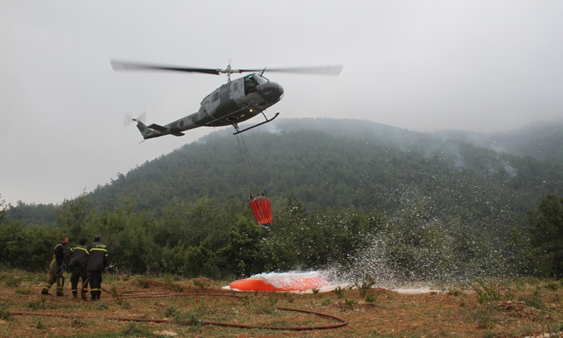 A Lebanese army helicopter transports water to put out a fire in the pine forest in Danniyeh, Lebanon, on June 8, 2022.(Photo: Xinhua)