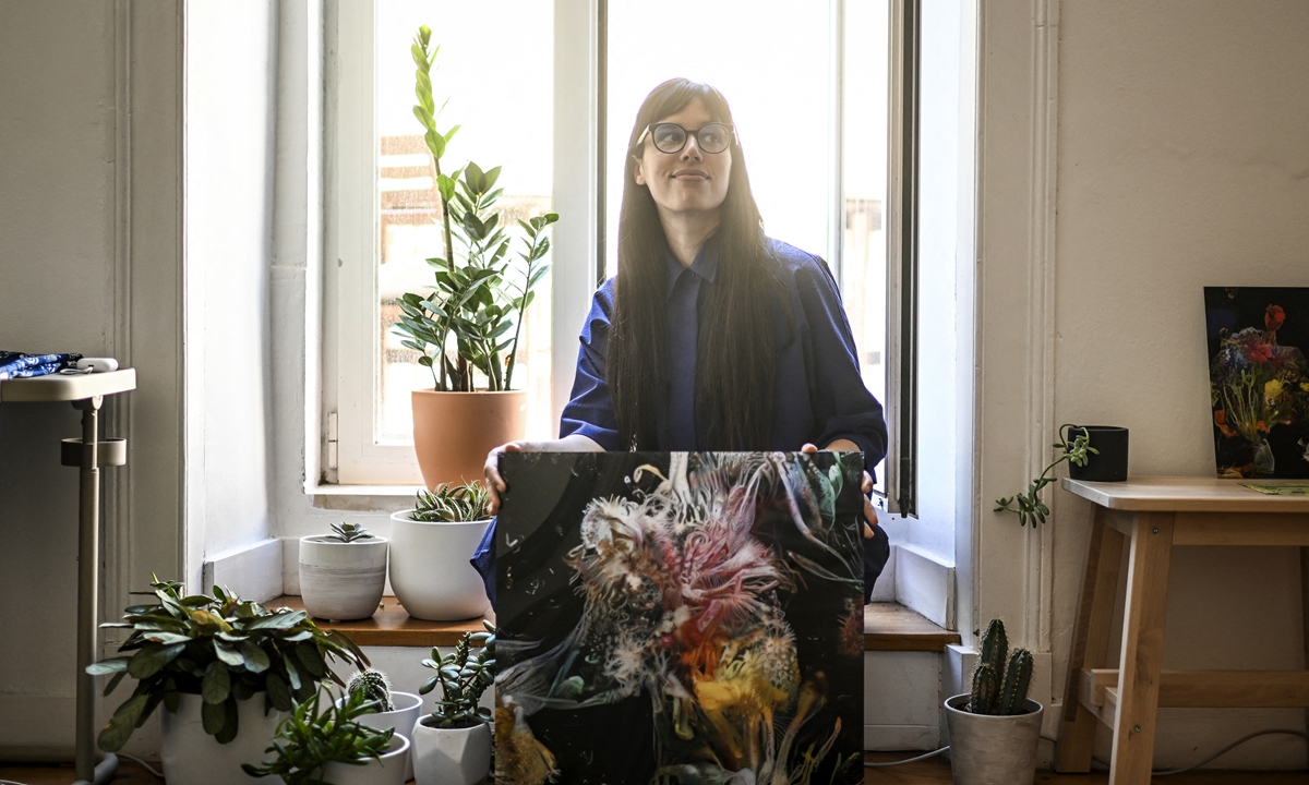 Argentinian artist Sofia Crespo holds one of her works as she poses for a photo at her home in Lisbon, Portugal on June 8, 2022. Photo: AFP