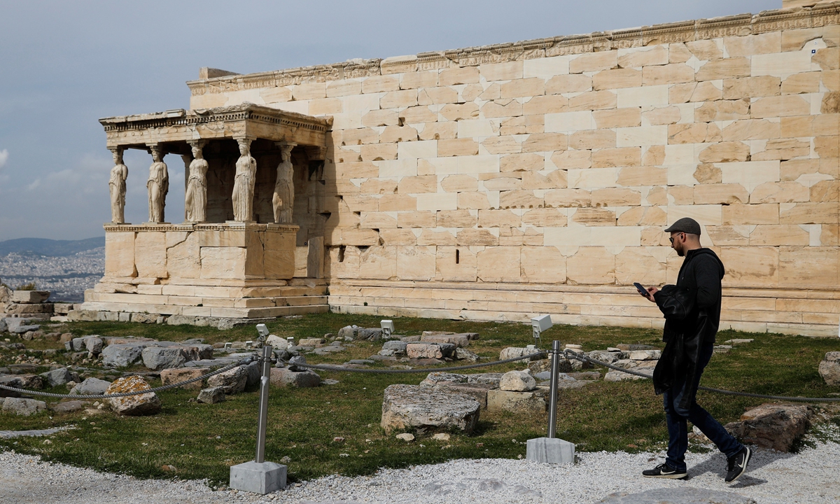 A tourist walks past the Erechtheion temple atop Acropolis hill in Athens, Greece, on February 16, 2022. Photo: VCG