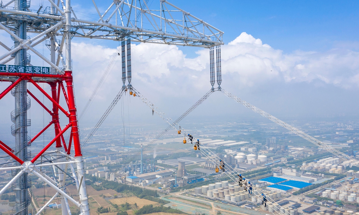 Workers climb power lines to complete a transmission grid over the Yangtze River near Wuxi, East China’s Jiangsu Province on June 13, 2022. The line allows optimized distribution across the river. In Jiangsu, industrial firms have fully resumed work, and industrial electricity use in Suzhou grew 26.5 percent year-on-year in May. Photo: cnsphoto