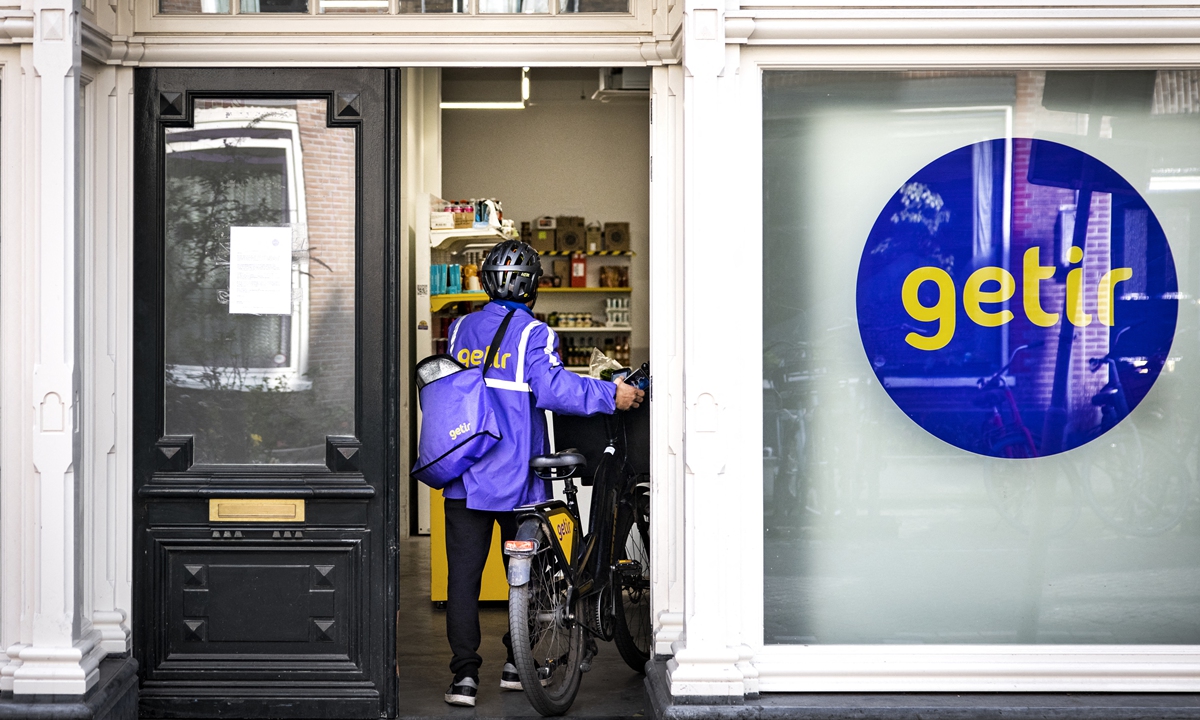 A flash delivery person enters a store by Getir in the center of Amsterdam, the Netherlands on March 29, 2022. Photo: AFP